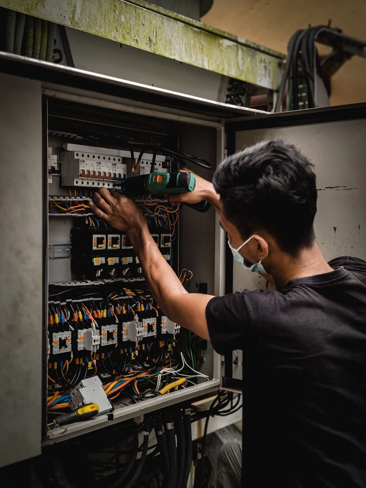 An electrician working inside a large distribution board, for commercial electrical in London