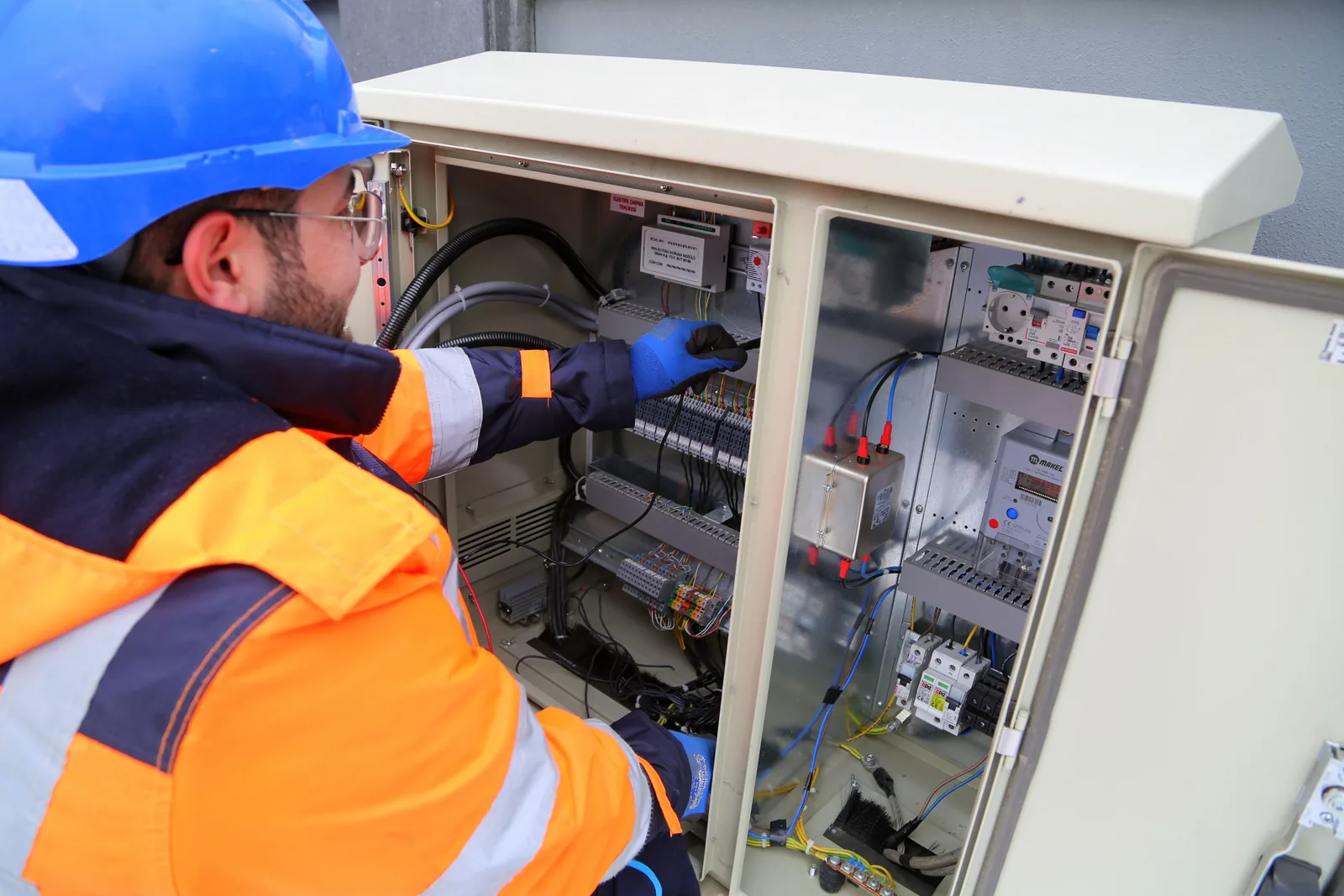 An electrician working in an outdoor service cabinet, for maintenance plans in London